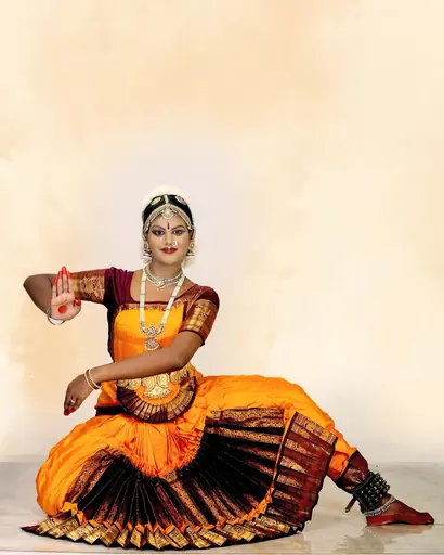 Classical dancer in a seated pose against a soft backdrop