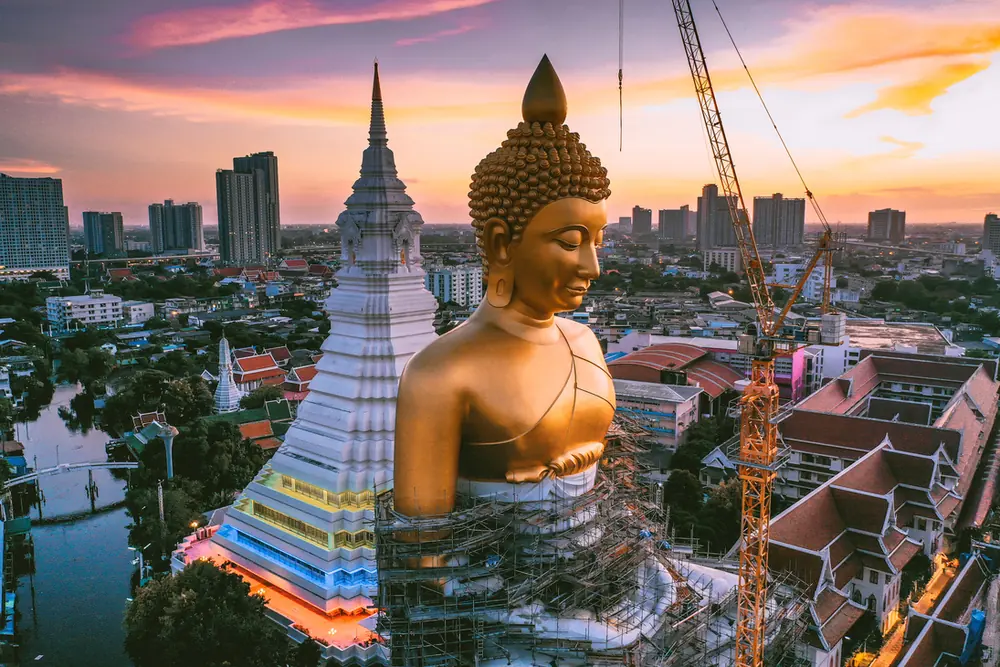 Golden Buddha and a temple spire at sunset