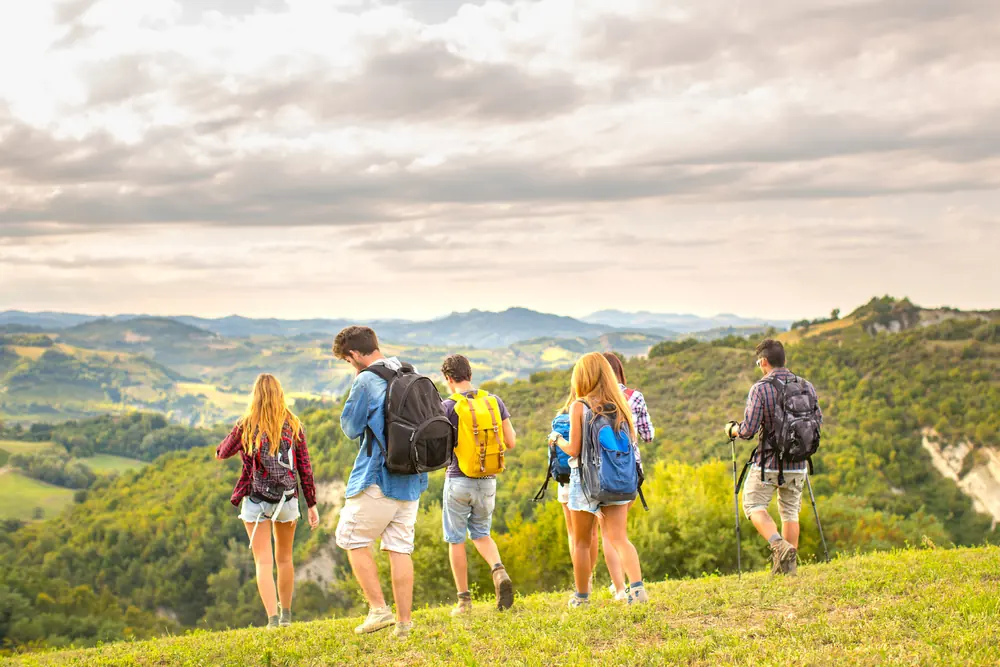 Group of friends trekking across green hills
